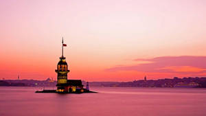 A Lighthouse Is Floating In The Water At Sunset Wallpaper