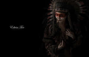 A Lone Blackfeet Native American Man Stands On The Slope Of A Mountain And Looks Out At The Horizon Wallpaper