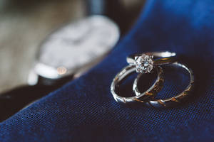 A Macro Shot Of Two Dazzling Diamond Rings On Top Of A Wristwatch. Wallpaper