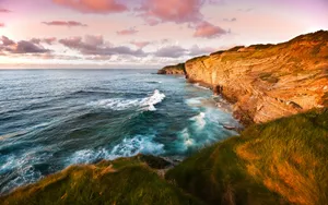 A Majestic Coastal Scene Under A Pink-clouded Sky Wallpaper
