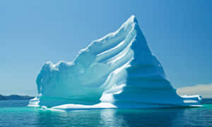 A Majestic Iceberg Floating In Blue Waters Wallpaper