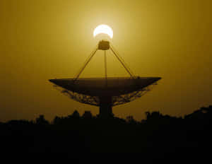 A Majestic Radio Telescope Standing Tall Under A Clear Blue Sky. Wallpaper