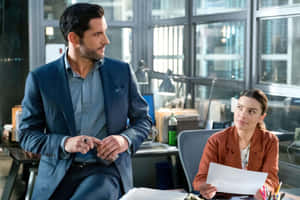 A Man And Woman In A Business Suit Sitting At A Desk Wallpaper