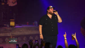 A Man In A Black Shirt Singing Into A Microphone Wallpaper