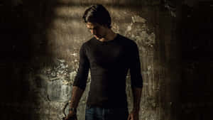 A Man In A Black Shirt Standing In Front Of A Wall Wallpaper