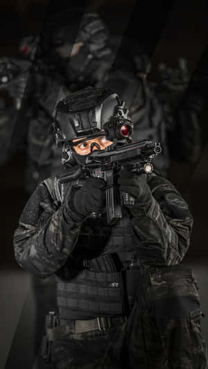 A Man In A Black Uniform Is Holding A Gun Wallpaper