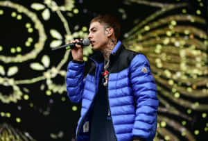 A Man In A Blue Jacket Singing Into A Microphone Wallpaper