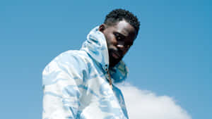 A Man In A Blue Jacket Standing On A Rock Wallpaper