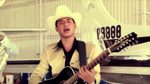 A Man In A Cowboy Hat Is Playing Guitar In Front Of A Plane Wallpaper