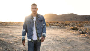 A Man In A Denim Jacket Standing In The Desert Wallpaper