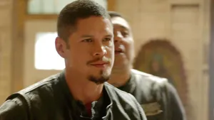 A Man In A Leather Jacket Is Standing Next To Another Man Wallpaper