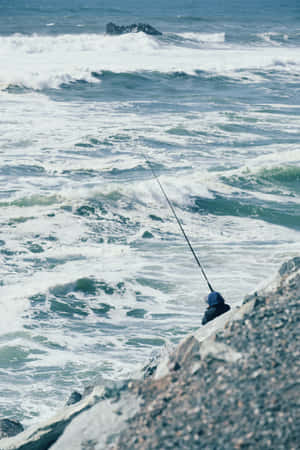 A Man Is Fishing Off The Coast Wallpaper