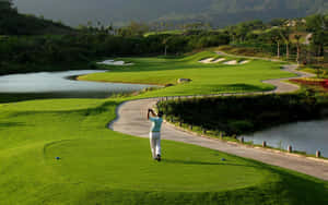 A Man Is Playing Golf On A Green Course Wallpaper