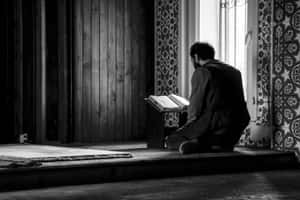 A Man Is Sitting In Front Of A Window Reading A Book Wallpaper