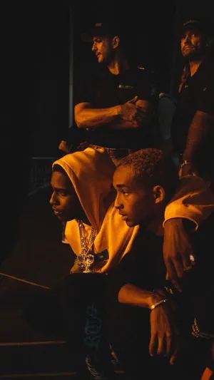 A Man Is Sitting On The Ground With A Man Behind Him Wallpaper