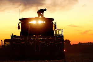 A Man Is Standing On A Combine Harvester Wallpaper