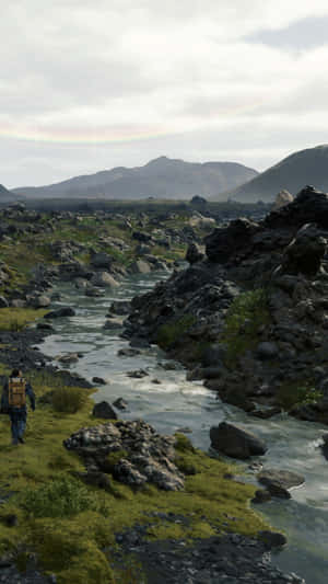 A Man Is Walking Along A River Wallpaper