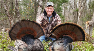 A Man Kneeling Down With Two Turkeys Wallpaper