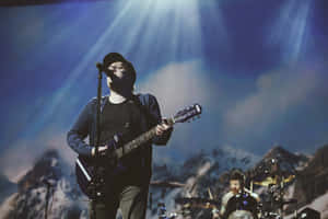 A Man Playing Guitar On Stage With A Microphone Wallpaper