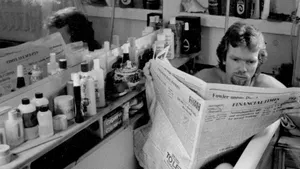 A Man Reading A Newspaper In A Bathroom Wallpaper