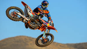 A Man Riding A Dirt Bike In The Air Wallpaper