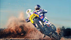 A Man Riding A Dirt Bike On A Dirt Track Wallpaper