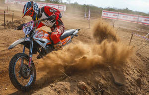 A Man Riding A Dirt Bike On A Dirt Track Wallpaper