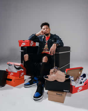 A Man Sitting In A Chair With A Lot Of Shoes Wallpaper