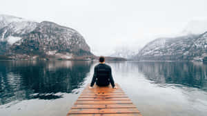 A Man Sitting On A Dock In The Snow Wallpaper