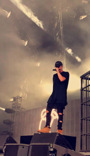 A Man Standing On Stage With A Microphone Wallpaper