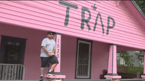 A Man Standing On The Front Porch Of A Pink House Wallpaper