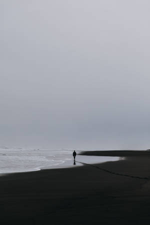 A Man Walking Alone On The Beach With His Phone Wallpaper