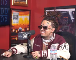 A Man With Dreadlocks Sitting In Front Of A Microphone Wallpaper