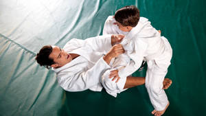 A Mentor Guiding A Young Talent In Brazilian Jiu-jitsu Wallpaper