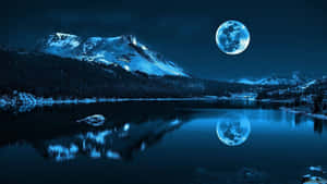 A Moon Is Reflected In A Lake With Mountains Wallpaper