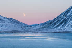 A Moon Rises Over A Mountain And Water Wallpaper