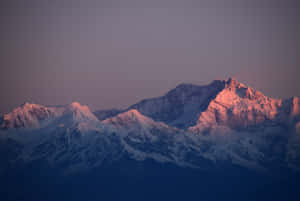 A Mountain Range Is Lit Up At Sunset Wallpaper