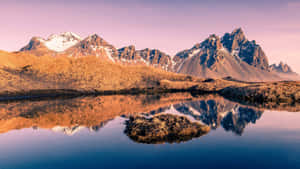 A Mountain Range Is Reflected In A Lake Wallpaper