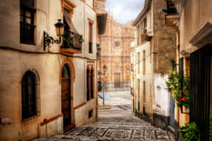 A Narrow Cobblestone Street With A Church In The Background Wallpaper