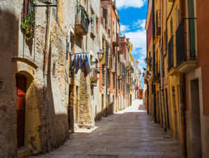 A Narrow Street With Buildings And A Laundry Line Wallpaper