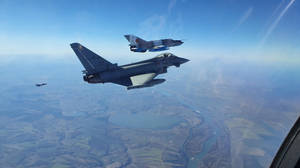 A Pair Of Fighter Jets Flying In The Sky Wallpaper