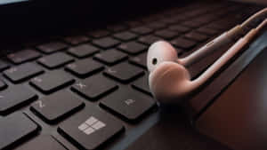 A Pair Of Headphones On A Laptop Keyboard Wallpaper