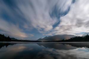 A Peaceful Lake Surrounded By A Dim Cloudy Sky. Wallpaper