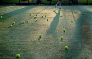 A Perfectly White Tennis Ball Bouncing On A Green Court Wallpaper