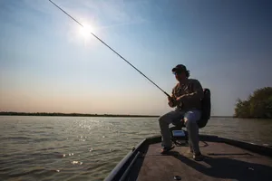A Person Holding A Fishing Rod At The Riverside Wallpaper