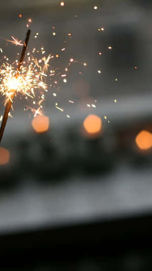 A Person Holding A Sparkler In Front Of Candles Wallpaper