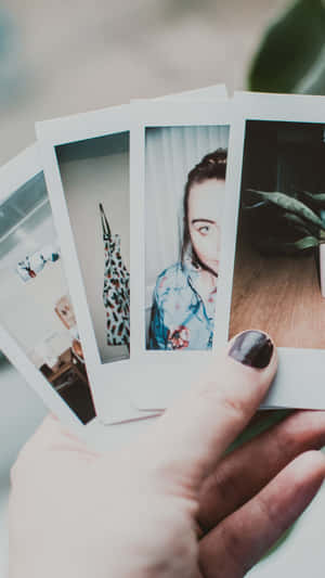 A Person Holding Up A Set Of Polaroid Photos Wallpaper