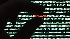 A Person Is Holding A Hand Up To A Computer Screen With The Word Malware Wallpaper