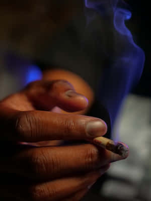 A Person Is Smoking A Cigarette In A Dark Room Wallpaper