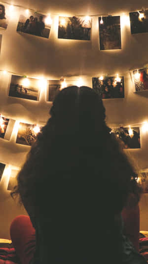 A Person Sitting On A Bed With Pictures Hanging On The Wall Wallpaper